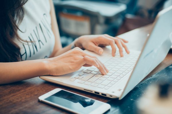 woman's hands busy working on her laptop beautiful young hipster woman's hands busy working on her laptop sitting at wooden table in a coffee shop